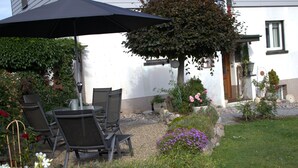 A house with a patio area featuring outdoor furniture and a stone wall. - Apartment 'Am Brunnen' with Shared Terrace, Shared Garden and Wi-Fi (Titisee-Neustadt)