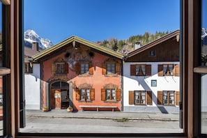 Un bâtiment traditionnel avec une façade en bois, un banc à l’extérieur et une montagne en arrière-plan.