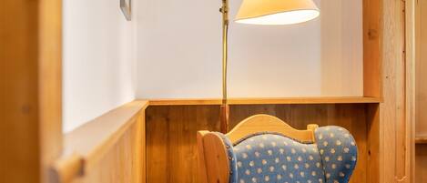 Een houten bank met een blauw gestreept kussen, een vloerlamp en een houten wand.