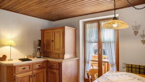 Eine Küche mit Holzschränken, einem Tisch und einer Hängelampe.