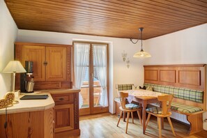 A wooden kitchen with a dining table, chairs, a bench, and a coffee machine. - Apartment 'Karwendelblick' with Mountain View, Balcony and Wi-Fi (Mittenwald)