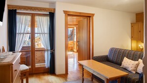 Ein Zimmer mit Holztisch, einer Couch, einem Holzschrank und einer Tür zu einem Außenbereich.