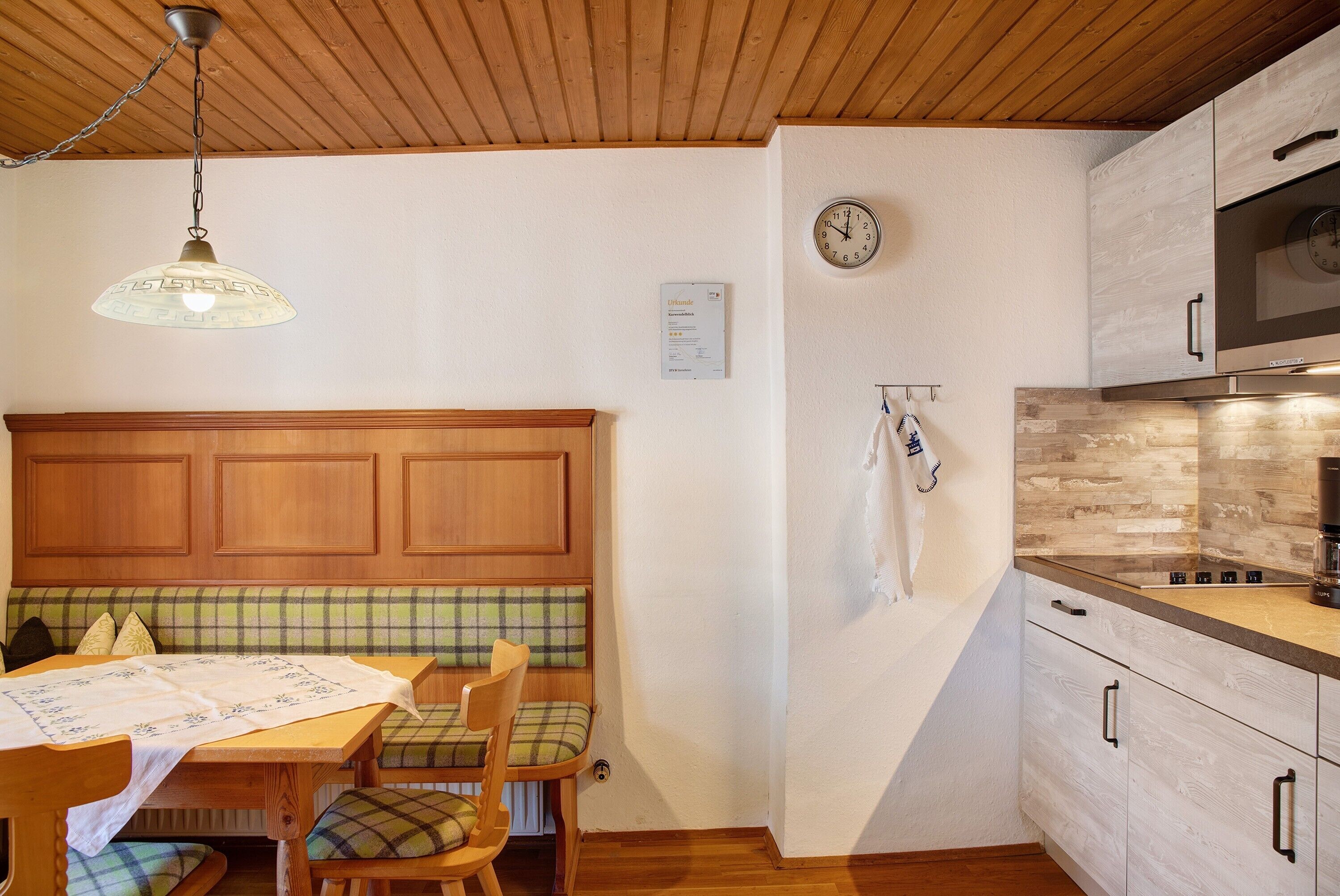 A kitchen with wooden cabinets, a clock, and a hanging towel.