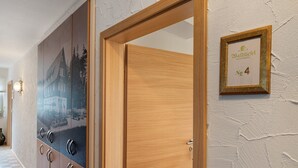 A hallway with a wooden door, a wall-mounted sign, and a checkered floor. - Room 'Panorama' with Shared Terrace, Shared Garden and Wi-Fi (Dornstetten)
