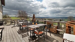 An outdoor deck with tables and chairs, a view of the countryside, and a sign for 'Baldiesel.' - Room 'Panorama' with Shared Terrace, Shared Garden and Wi-Fi (Dornstetten)