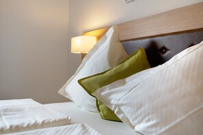 A hotel room with a neatly made bed, a headboard with a tufted design, and a bedside lamp.