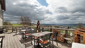 Eine Terrasse im Freien mit Tischen und Stühlen und Blick auf die Landschaft, mit einem Schild für 'Baldiesel'.