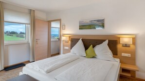 A bedroom with a bed, bedside lamps, a painting, and a view through a window. - Room 'Doppelzimmer 2 Premium' with Shared Terrace, Shared Garden and Wi-Fi (Dornstetten)