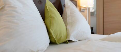 A bed with white bedding and a green pillow.