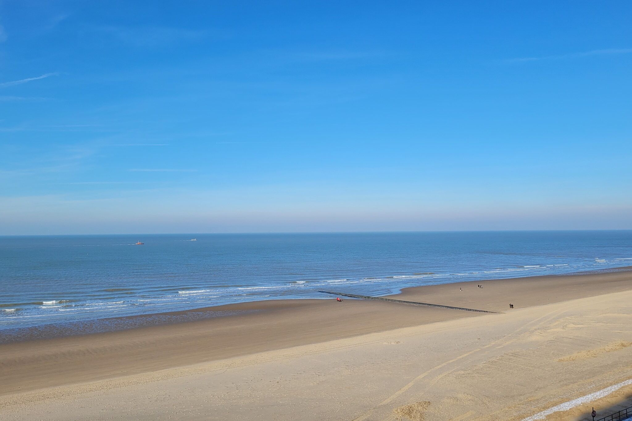 A beach with a clear sky, calm sea, and a sandy shore.