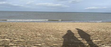 A beach with a shadow of two people on the sand.