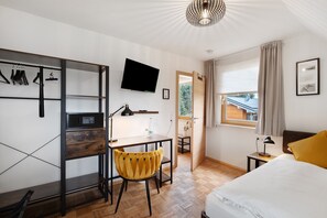 A hotel room with a bed, a desk with a chair, a TV, a window with curtains, and a door leading to a balcony. - Room 'Einzelzimmer 7' with Shared Terrace, Shared Garden and Wi-Fi (Dornstetten)