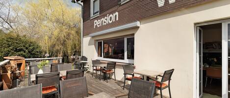 A patio area with outdoor seating and a building with a 'Pension' sign.