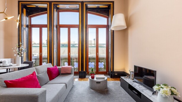 A modern living room with a sofa, coffee table, TV, and large windows with a view of a bridge. - Cosy apartment in heart of Porto (Oporto)