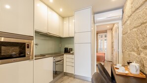 Una cocina moderna con armarios blancos, horno empotrado y microondas.