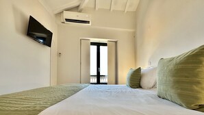 Una camera d'albergo con un letto, una televisione a schermo piatto montata a parete e un condizionatore d'aria.