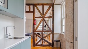 A kitchen with a modern sink, a wooden beam structure, and a dining area in the background. - Pretty apartment with modern comforts (Oporto)
