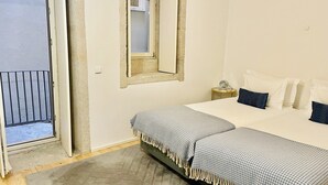 A bedroom with a bed, a bedside table, a mirror, and a door leading to a balcony.
