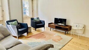A modern living room with a sofa, two armchairs, a TV, and a small table.