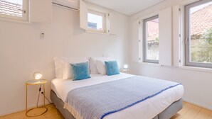A bedroom with a bed, bedside tables, a window, and an air conditioning unit.