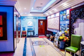 Welcome to the hotel lobby, featuring a reception desk and comfortable seating area with a view of the EXPO 2020 exhibition hall entrance.