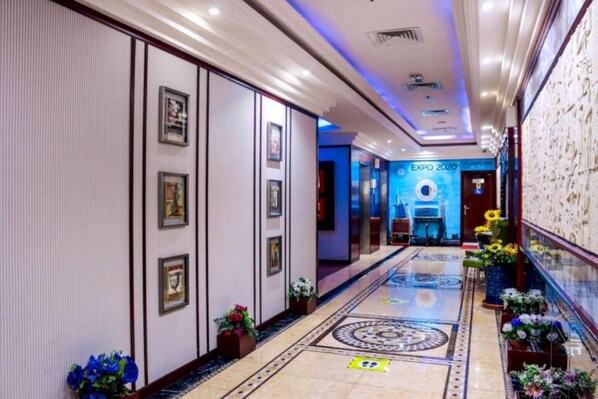 Stunning corridor with framed artwork, lush greenery, and a geometric patterned floor.