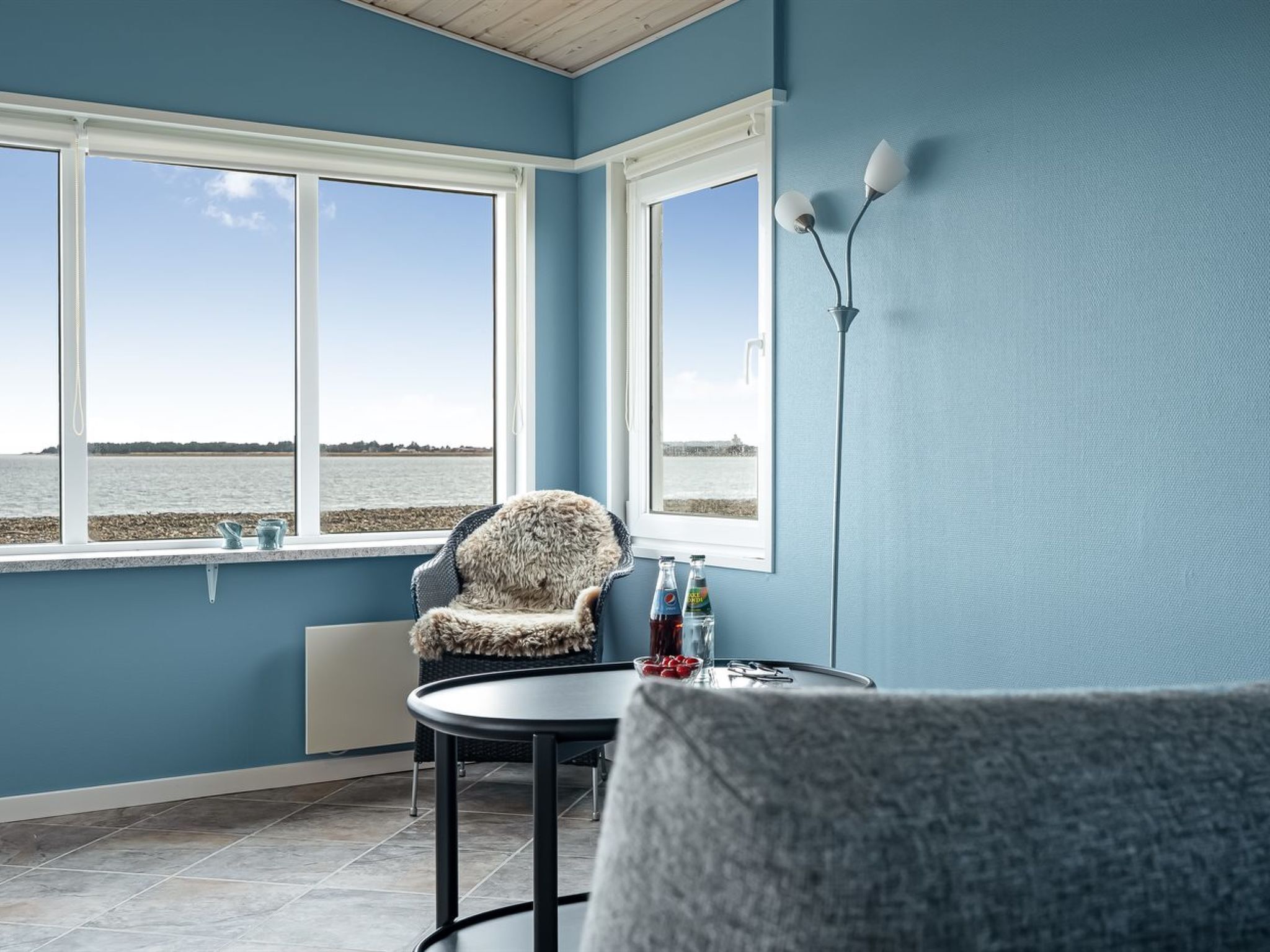 Ein Zimmer mit Meerblick, ein Sessel, ein Tisch und eine Lampe.