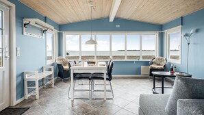 A dining area with a view of the sea, a wooden ceiling, and a blue wall. - "Nyalle" - 50m to the fjord by Interhome (Struer)