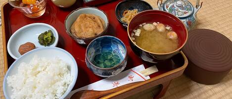 Una bandeja con diferentes alimentos, como arroz, sopa y verduras encurtidas.