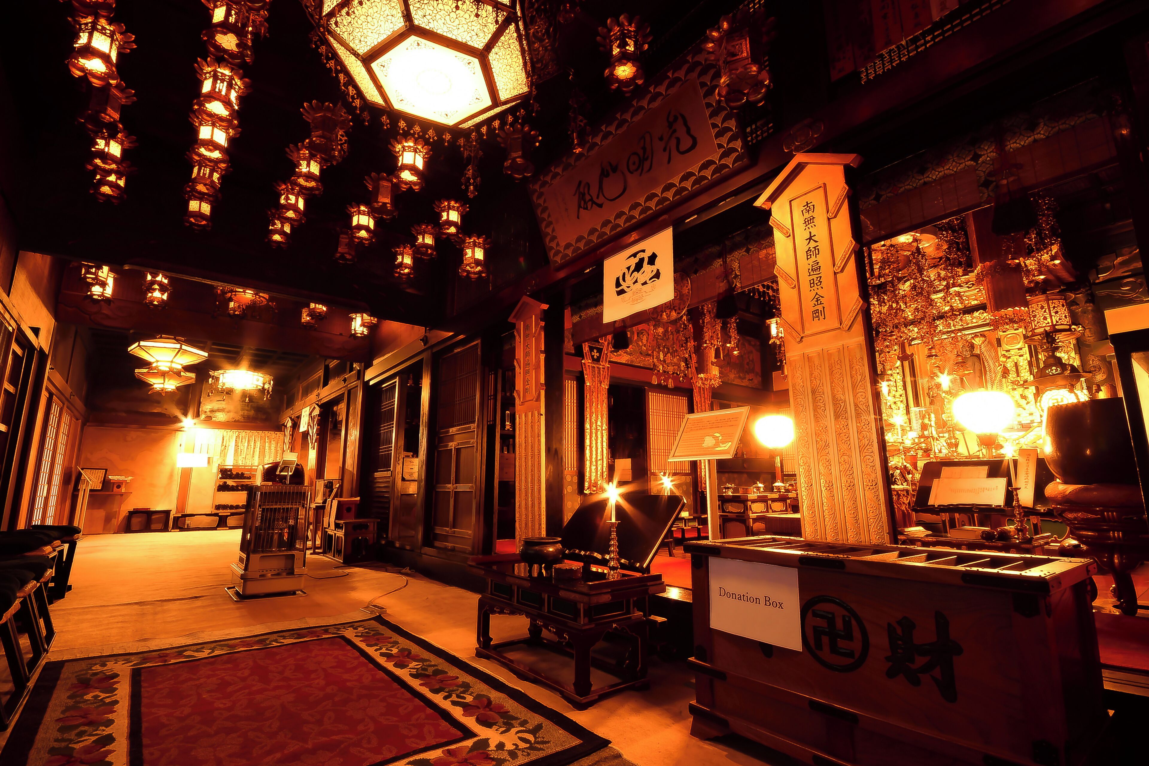 A traditional interior with hanging lanterns, a donation box, and a sign with Chinese characters.