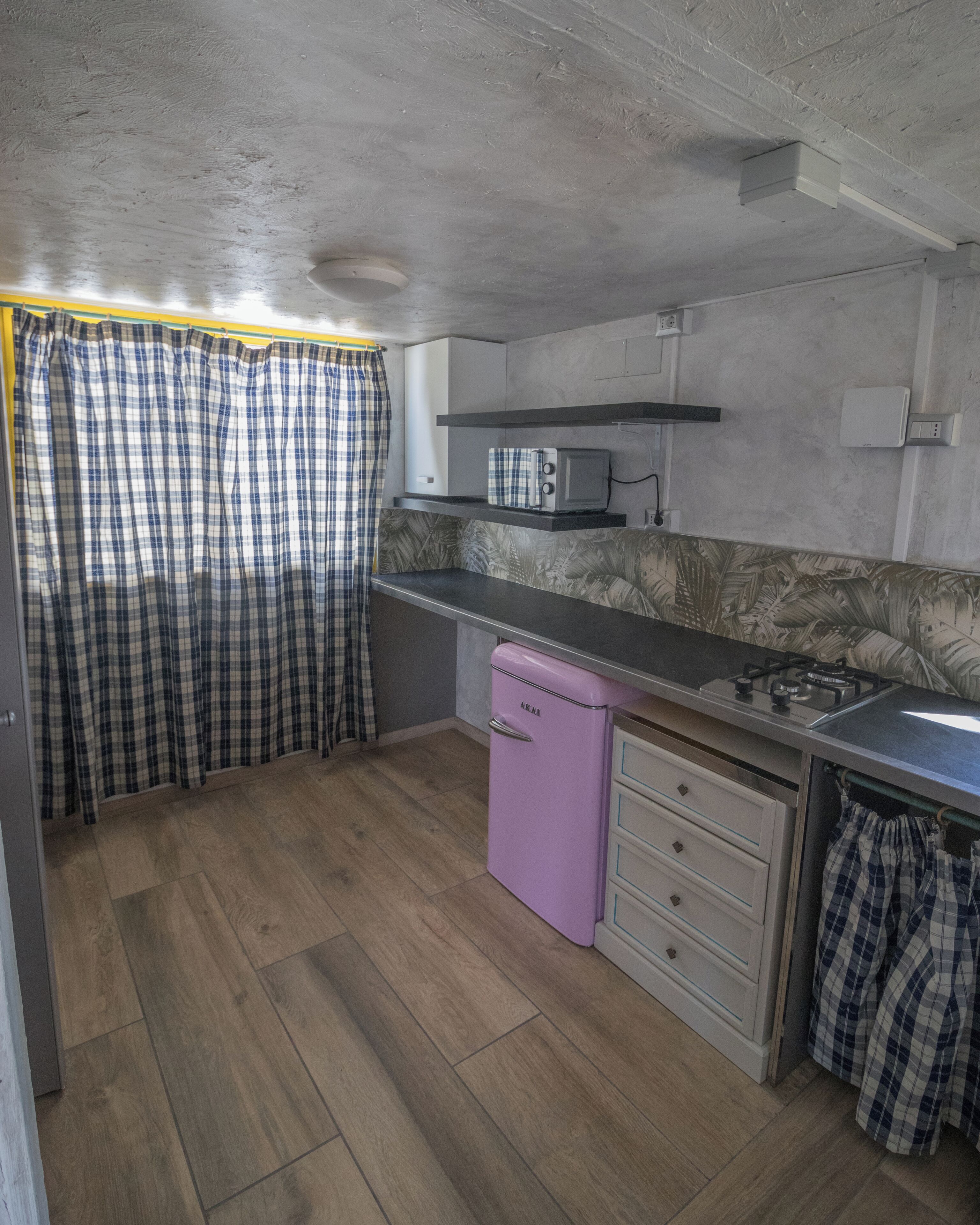 A compact kitchen with a microwave, stove, and a small refrigerator.