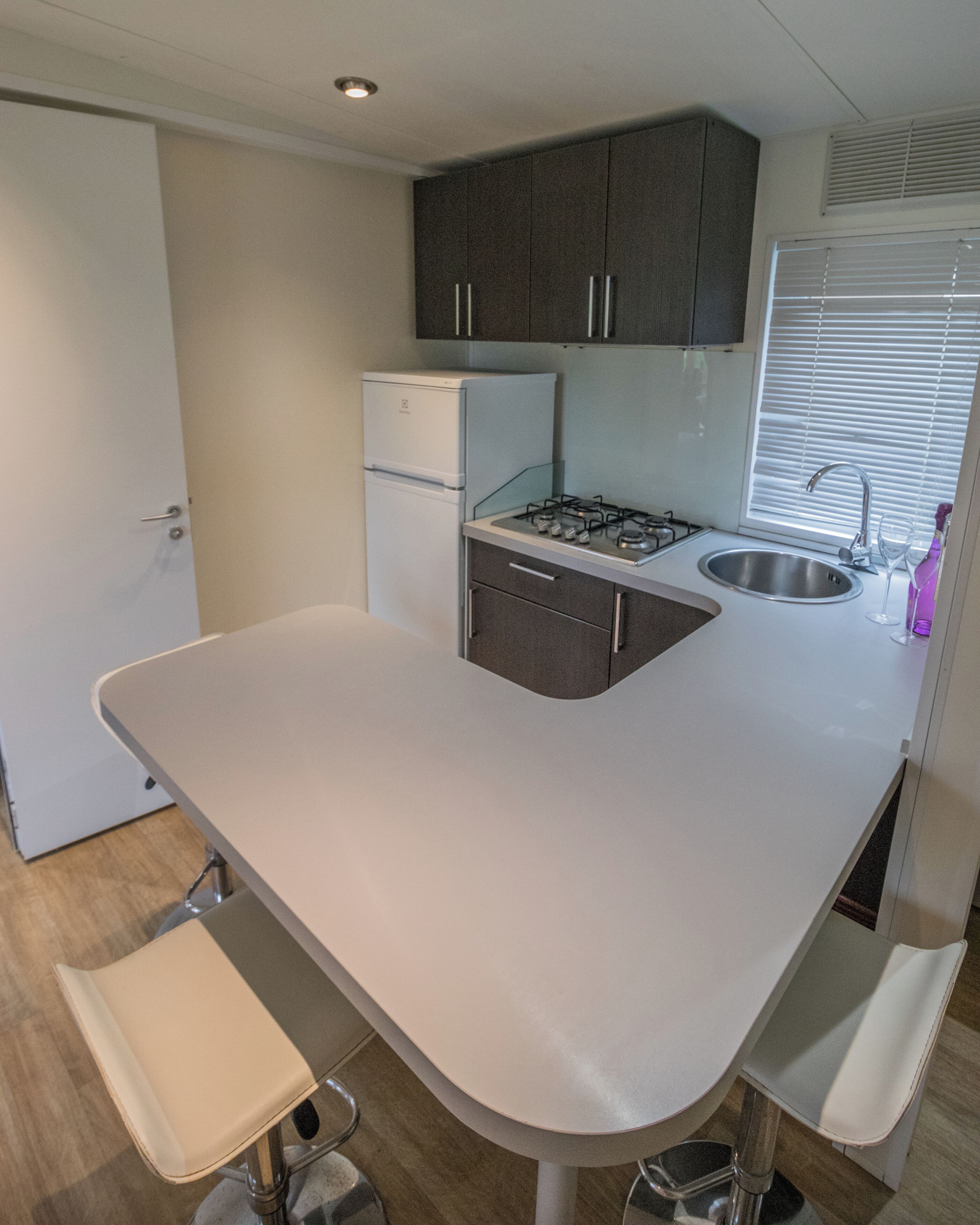 Una cocina compacta con estufa a gas, lavamanos y refrigerador.