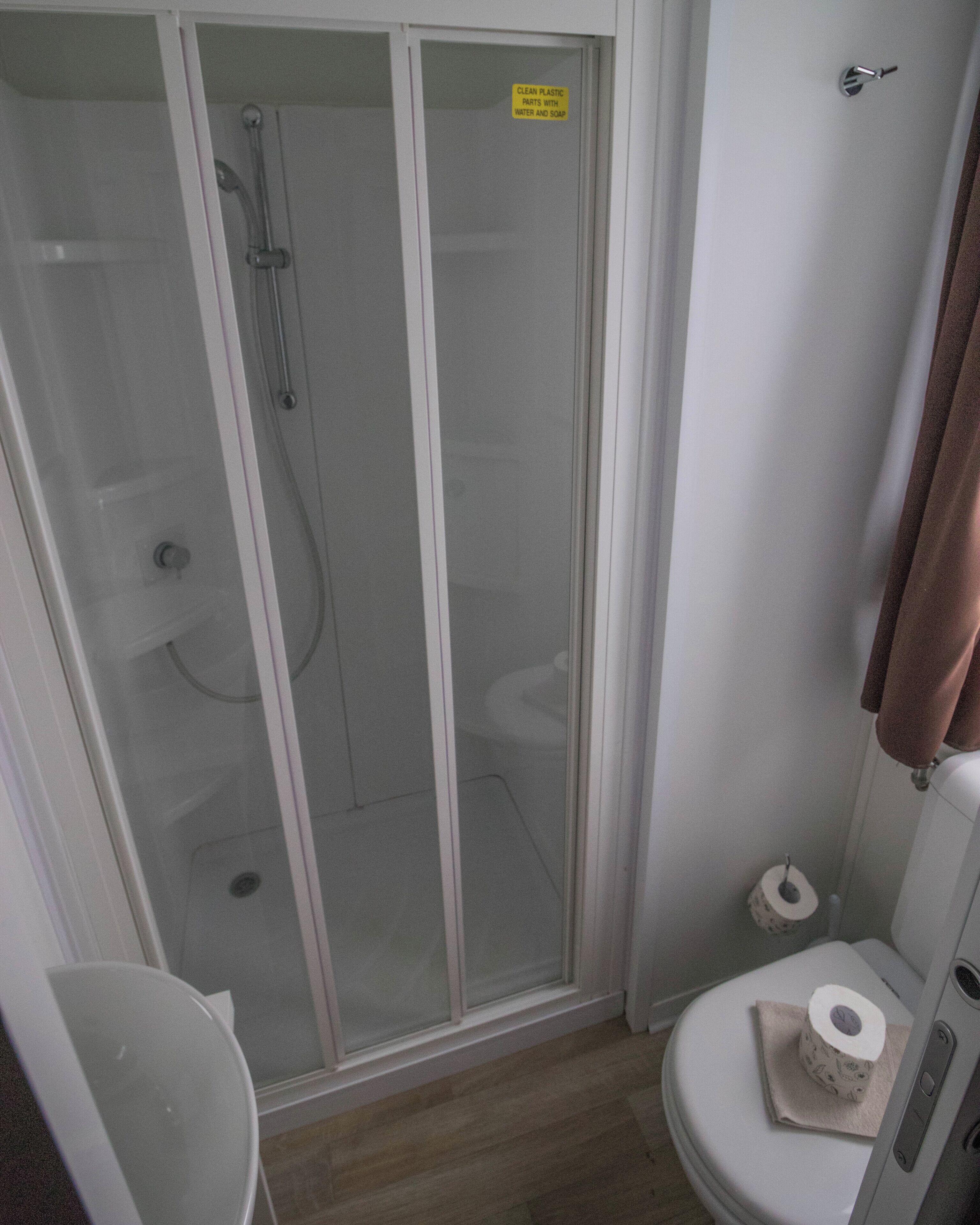 A bathroom with a glass-enclosed shower, a toilet, and a towel rack.