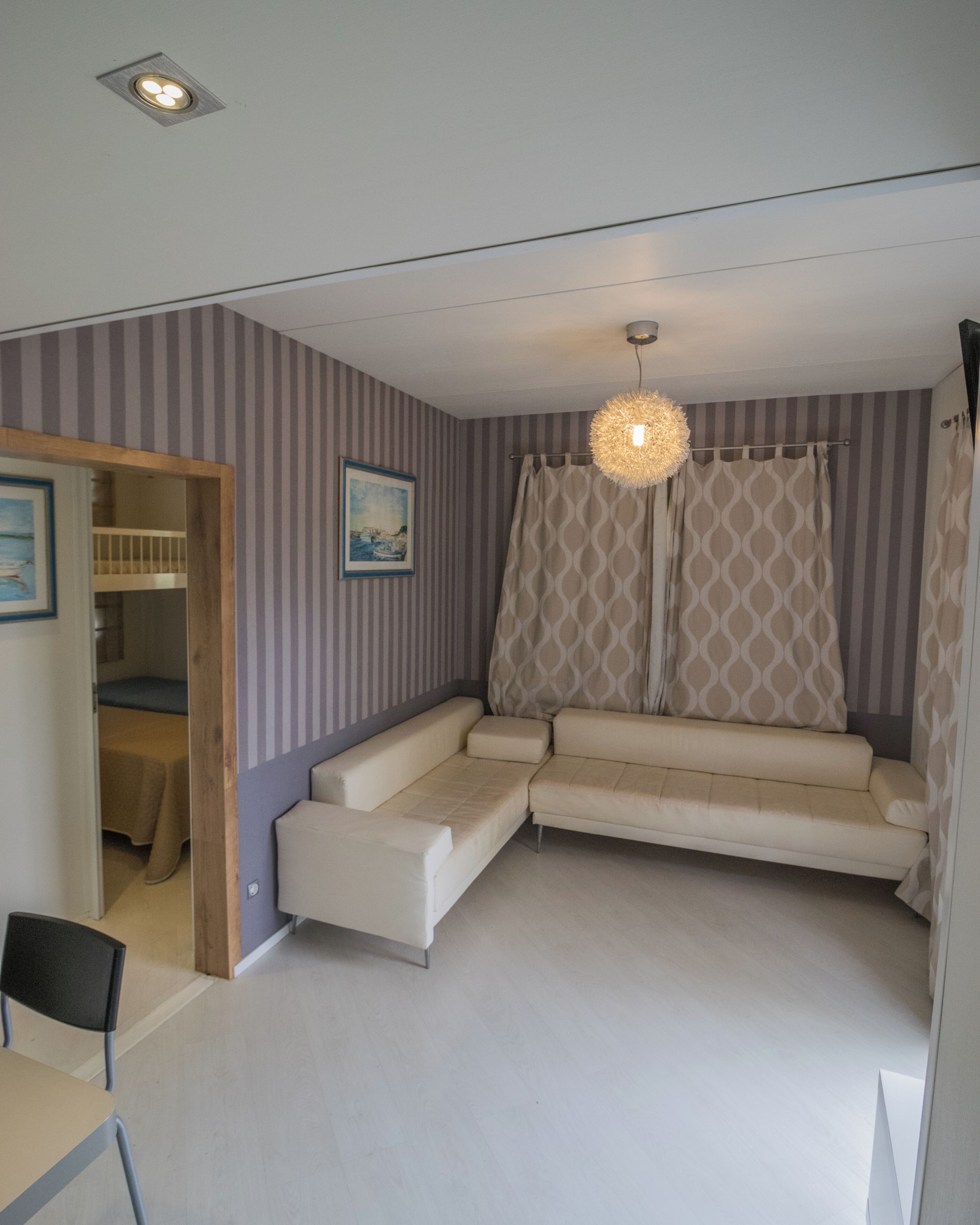 Una habitación con sofá, luz de techo y cortina estampada.