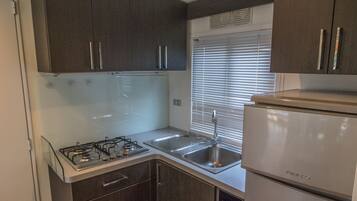A compact kitchen with dark cabinets, a stainless steel sink, a gas stove, and a built-in refrigerator.