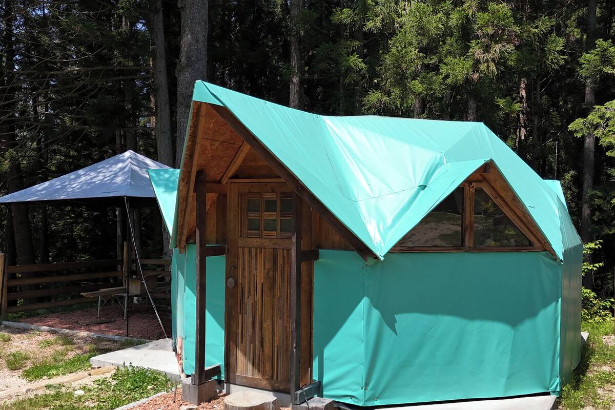 Une petite cabane à un seul étage, avec un toit en pente, une porte en bois et un petit porche.