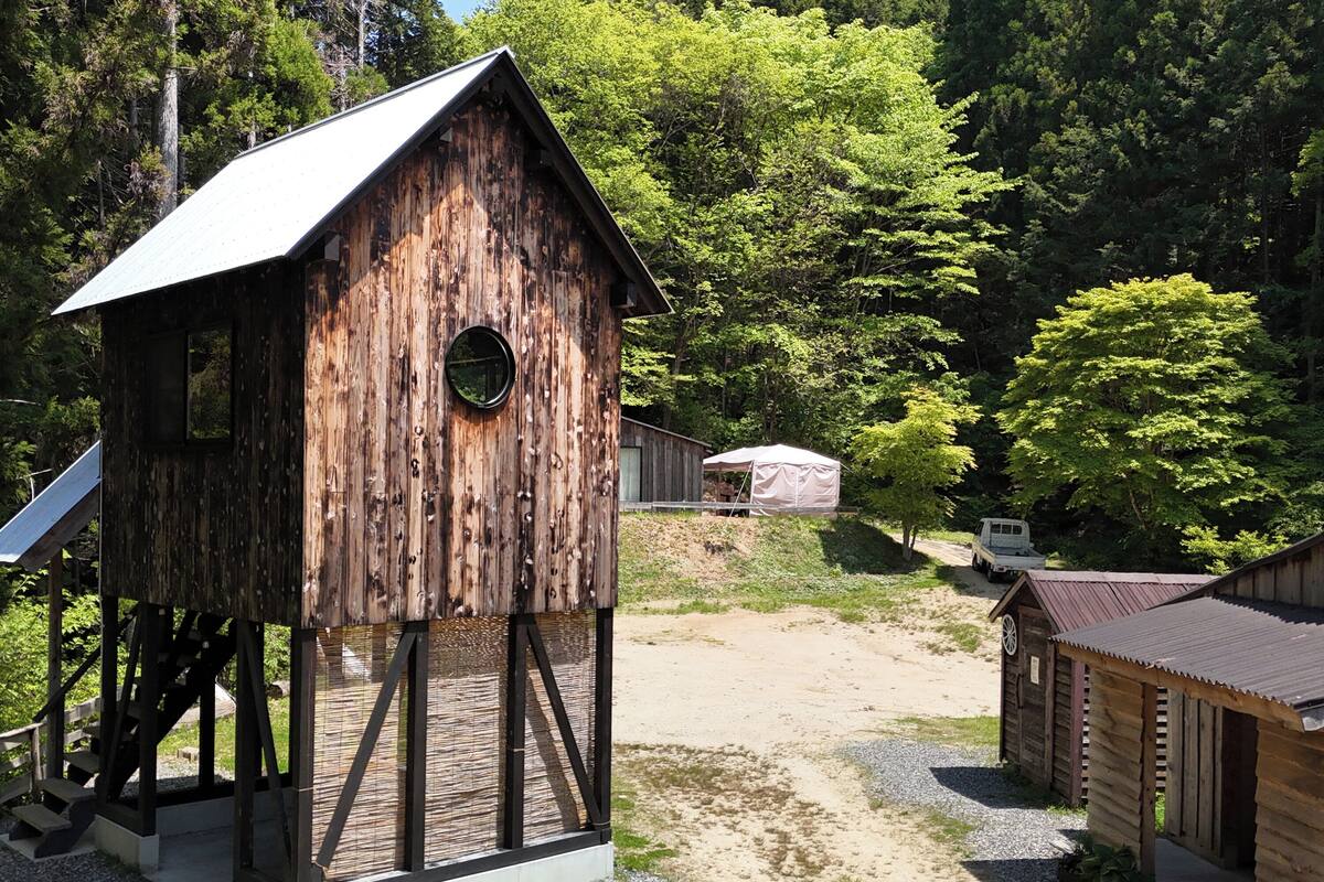 Une structure rustique en bois, dotée d’un toit en pente, d’une fenêtre circulaire et d’un escalier menant à une plateforme.