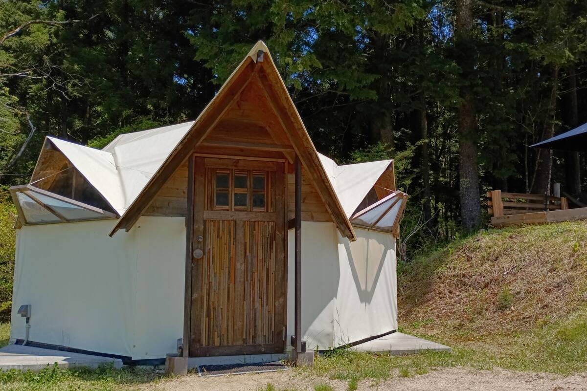 Une petite cabane à un seul étage, avec un toit en pente, une porte en bois et un petit porche.