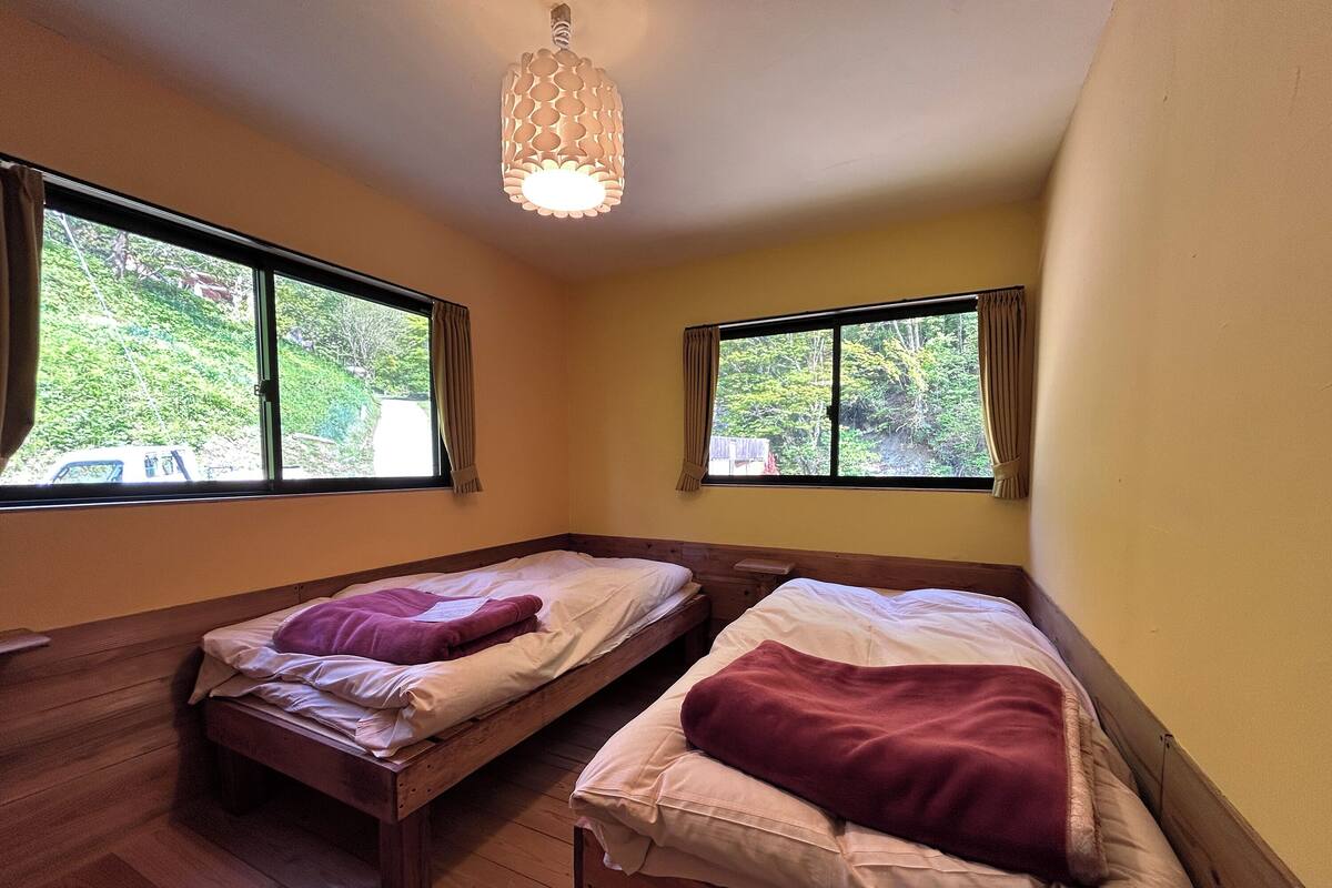 Une pièce avec deux lits en bois, un plancher en bois et un luminaire au plafond.