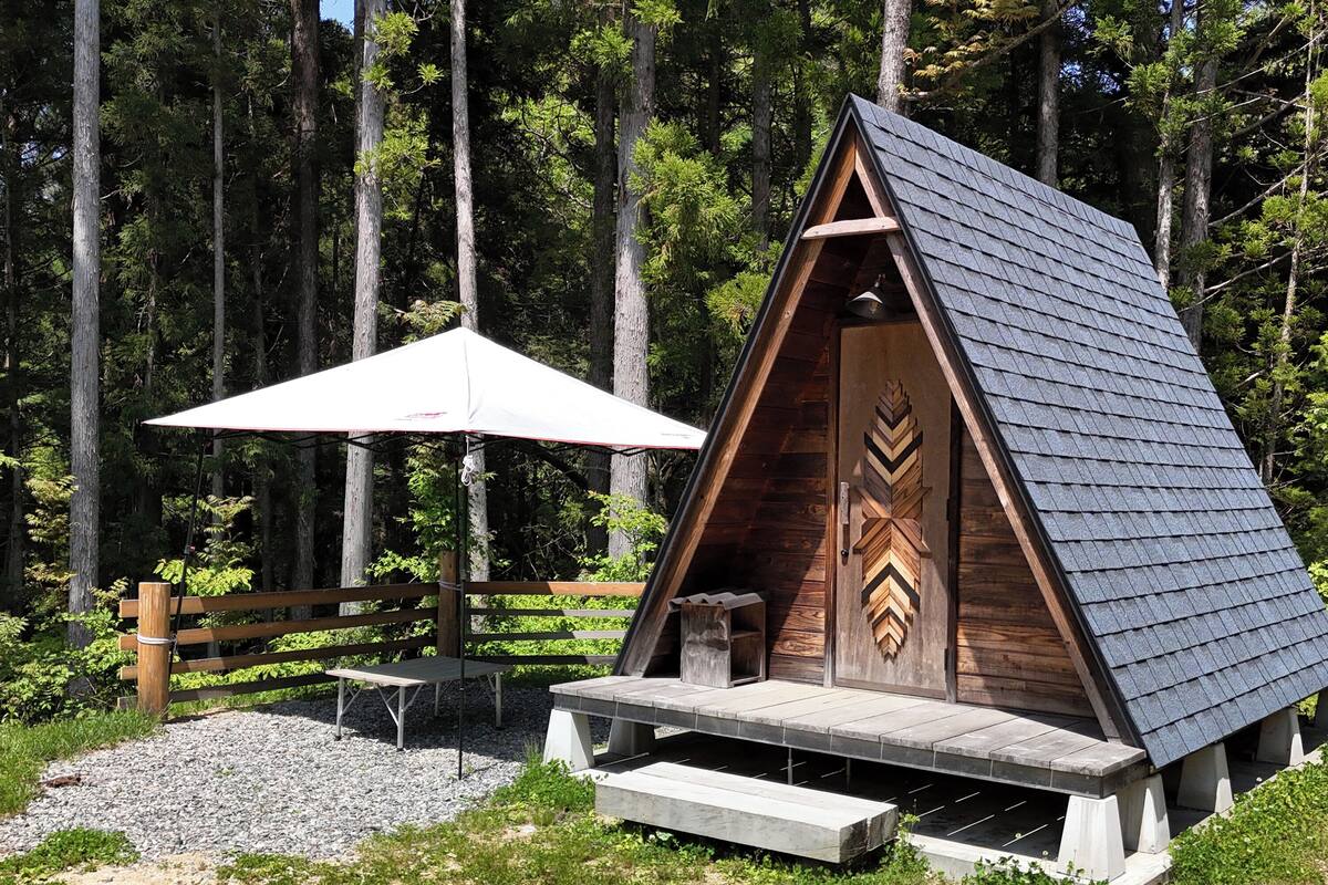 Une cabane en bois avec un toit à deux versants, une véranda et une table de pique-nique.