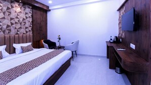 A modern hotel room with a large bed, a desk, a chair, and a TV mounted on the wall. - The Commune KASHI (Varanasi)