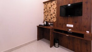 A small, private room with a wooden desk, a television mounted on the wall, and a geometric-patterned partition. - The Commune KASHI (Varanasi)