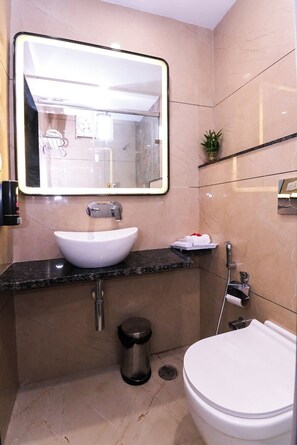 Un baño moderno con un lavabo blanco, un espejo grande, un inodoro y una zona de ducha.
