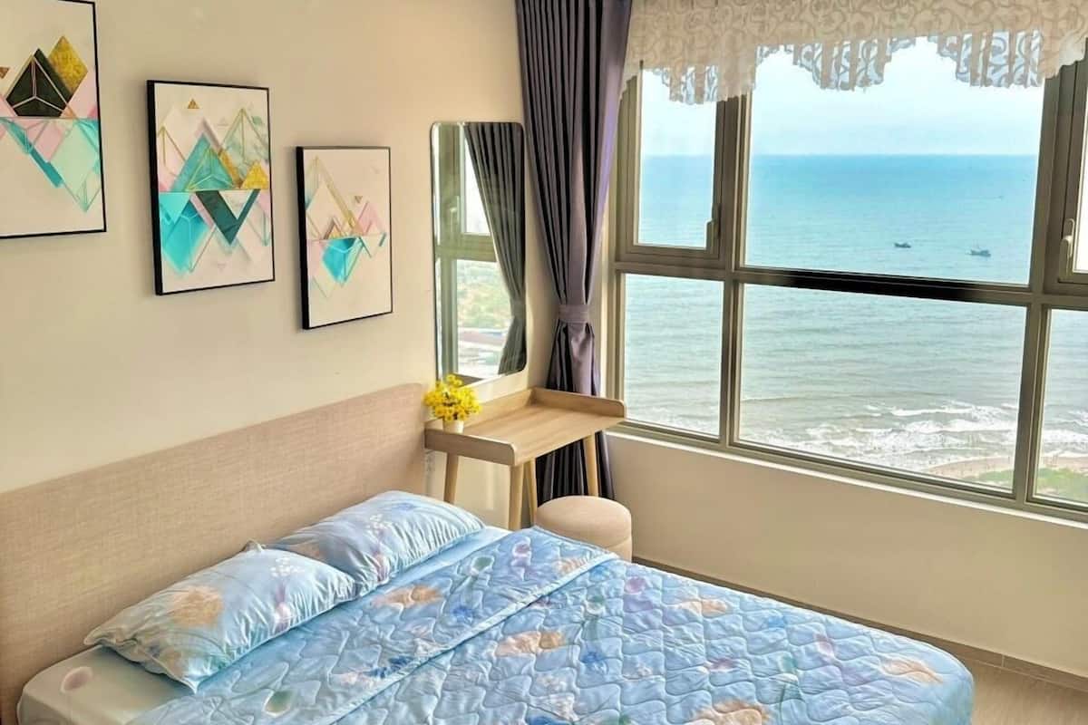 Une chambre avec un lit, un bureau et une vue sur la mer.