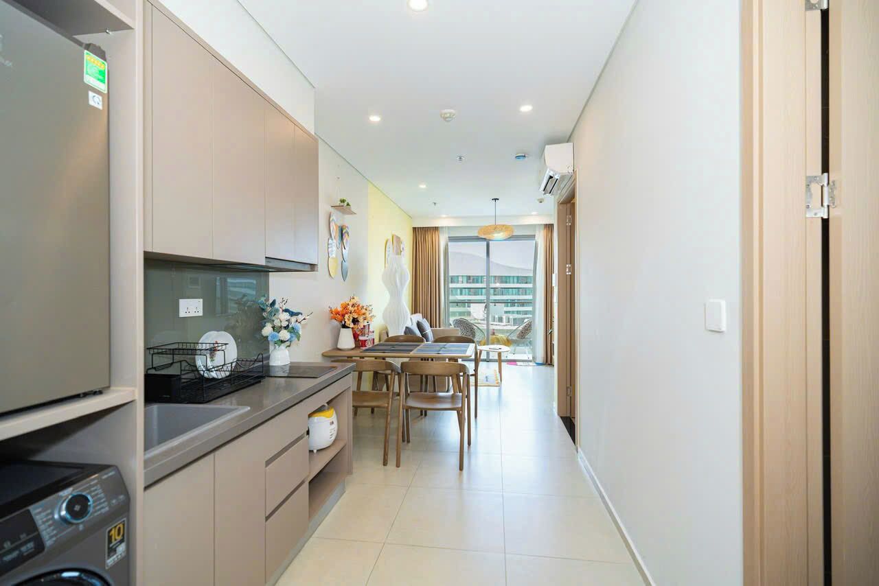 A modern kitchen with a built-in dishwasher, a dining area with a table and chairs, and a view of the city through large windows.