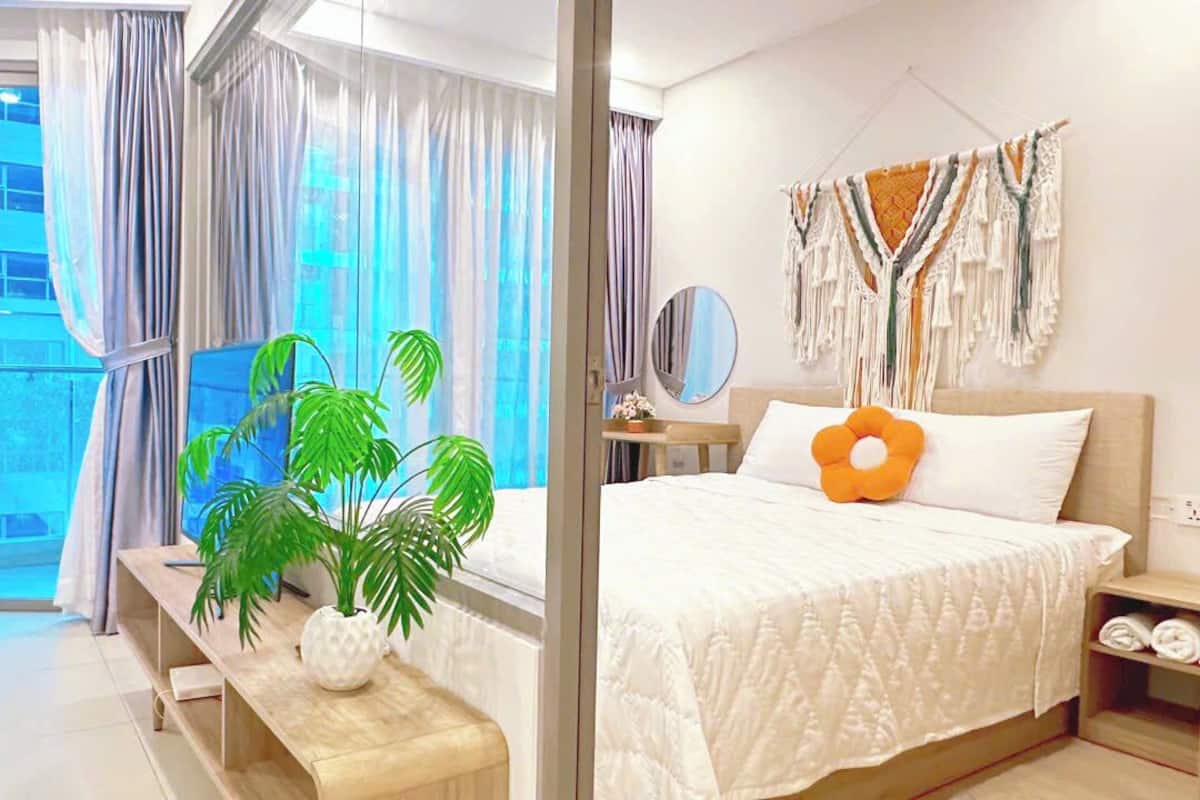 Une chambre moderne avec un grand lit, une table de chevet, un miroir et une vue sur l’extérieur grâce à une porte vitrée.