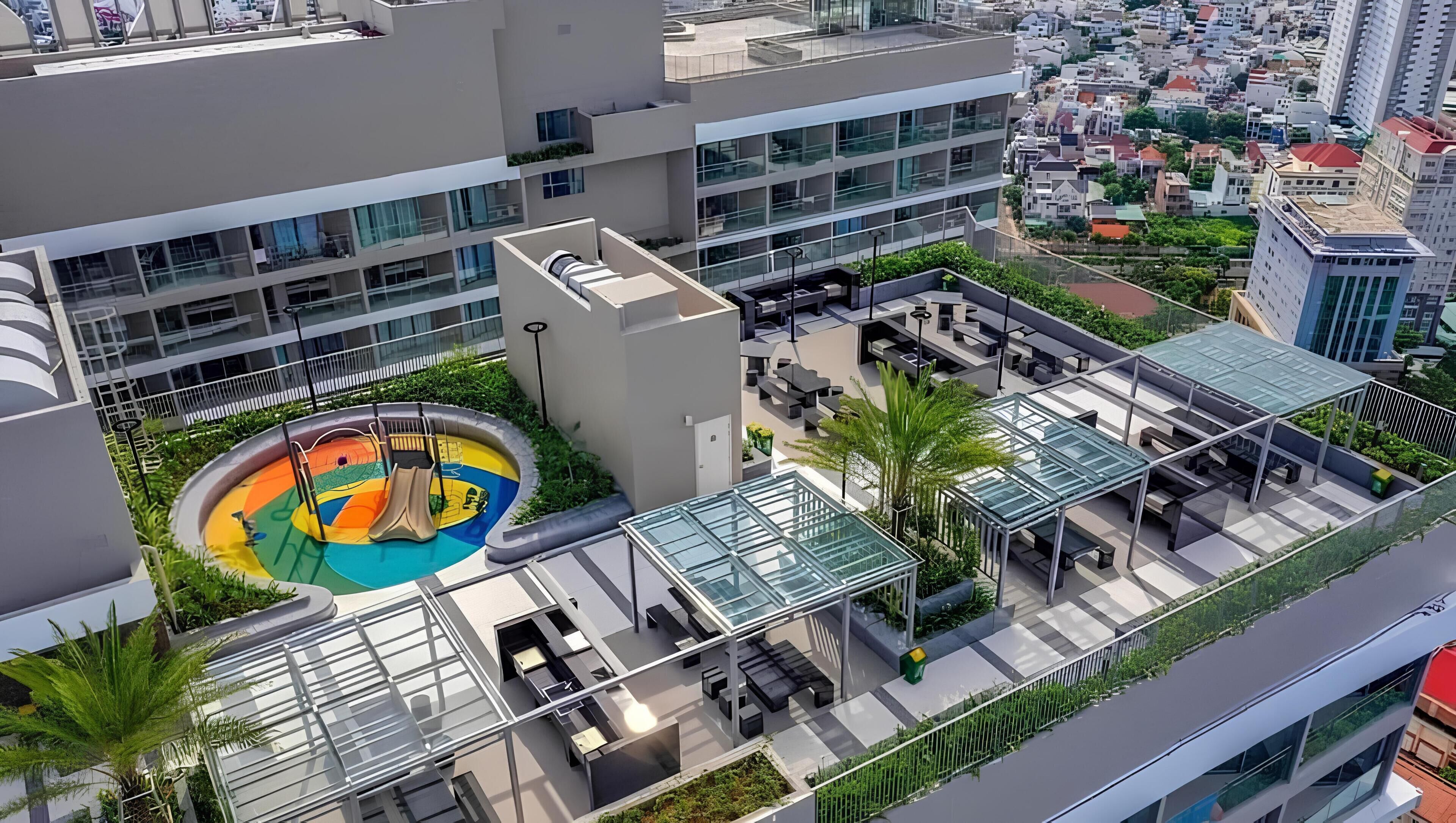Una azotea moderna con un tobogán colorido, asientos al aire libre y una zona con cerramientos de vidrio.