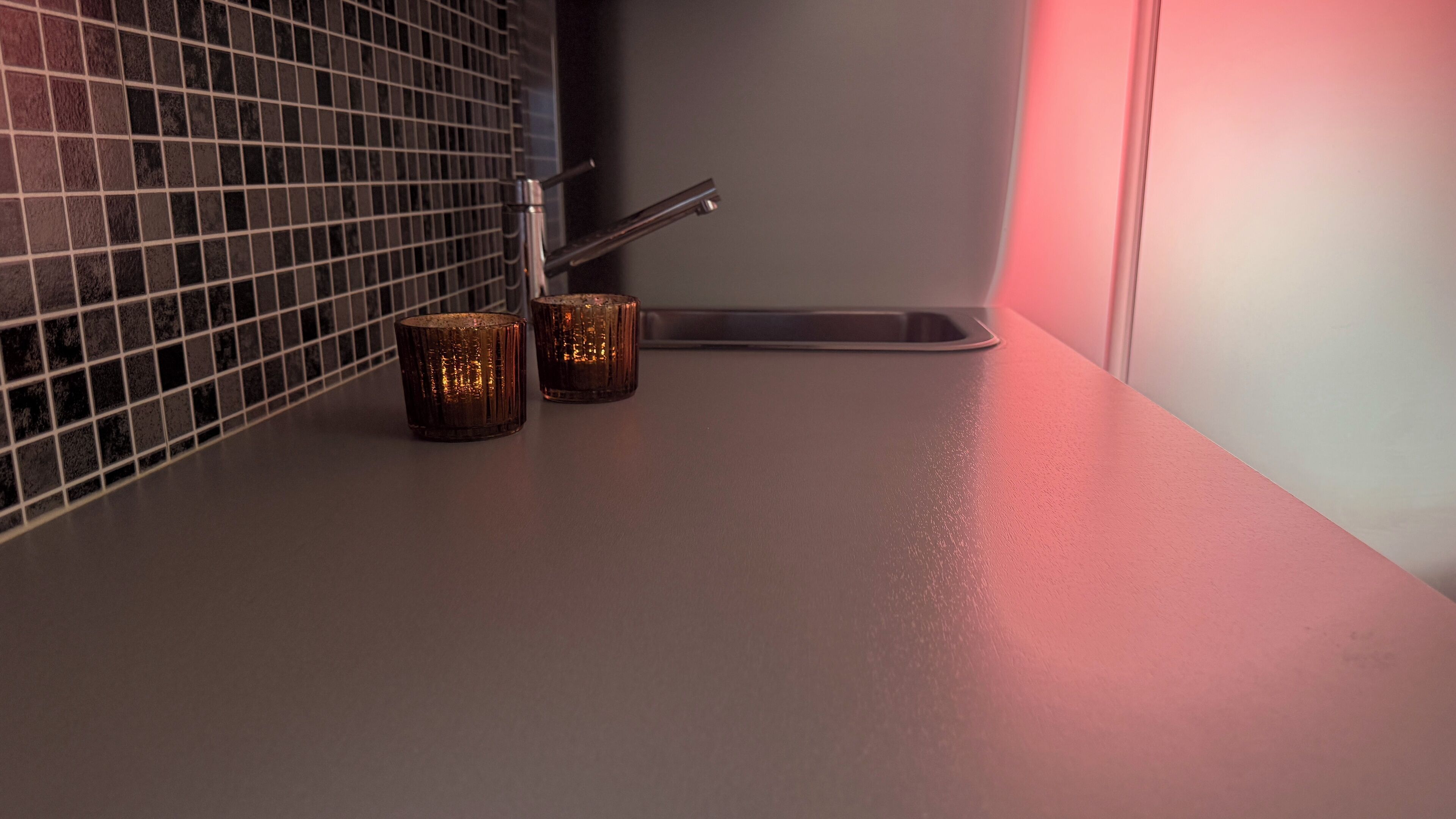 A kitchen counter with two metallic candle holders and a metal sink.