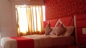 Un dormitorio moderno con una decoración en rojo y blanco, una cama con muchos almohadones, un ventilador de techo y un equipo de aire acondicionado.