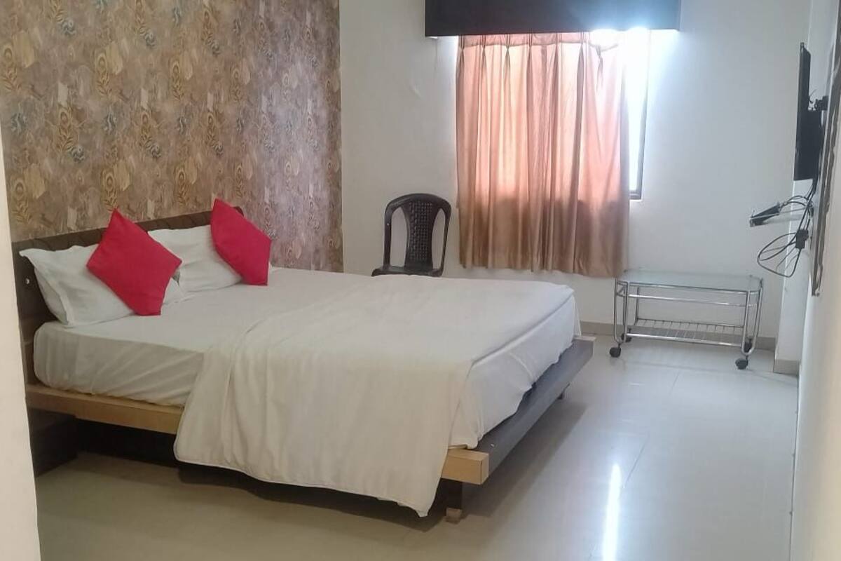 A bedroom with a bed, a chair, a radiator, and a window with curtains.